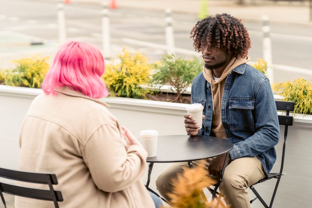 Two friends talking over coffee at an outdoor cafe